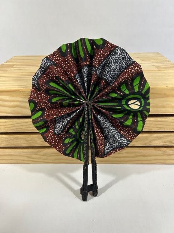 Elevate your style with our foldable handmade African fan from Ghana. Crafted with vibrant African wax print fabric and goat leather, this compact accessory is perfect for any occasion. Carry a piece of Ghana with you in your purse or bag. [Black Leather, Brown & Green Fabric] Embrace the artistry of Ghanaian craftsmanship. #Handmade #AfricanFashion #GhanaCrafts #WomenOwned #ShopWithPurpose