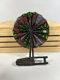 Elevate your style with our foldable handmade African fan from Ghana. Crafted with vibrant African wax print fabric and goat leather, this compact accessory is perfect for any occasion. Carry a piece of Ghana with you in your purse or bag. [Black Leather, Brown & Green Fabric] Embrace the artistry of Ghanaian craftsmanship. #Handmade #AfricanFashion #GhanaCrafts #WomenOwned #ShopWithPurpose