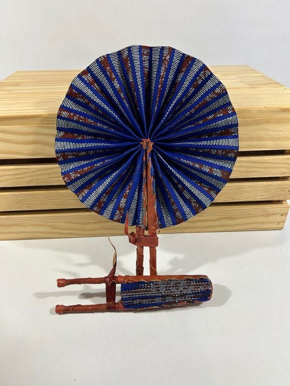 Discover Ghanaian artistry with our foldable handmade African fan. Made from vibrant African wax print fabric and goat leather, this compact accessory fits seamlessly into your purse or bag. Explore its elegance from every angle. [Brown Leather, Brown & Blue Fabric] Elevate your style effortlessly and support skilled artisans. #Handmade #AfricanFashion #GhanaCrafts #WomenOwned #ShopWithPurpose #BusankamWolaFoundation #HopeForWomenAndGirls