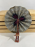 Discover Ghanaian artistry with our foldable handmade African fan. Made from vibrant African wax print fabric and goat leather, this compact accessory fits seamlessly into your purse or bag. Explore its elegance from every angle. [Brown Leather, Purple & Brown Fabric] Elevate your style effortlessly and support skilled artisans. #Handmade #AfricanFashion #GhanaCrafts #WomenOwned #ShopWithPurpose #BusankamWolaFoundation #HopeForWomenAndGirls