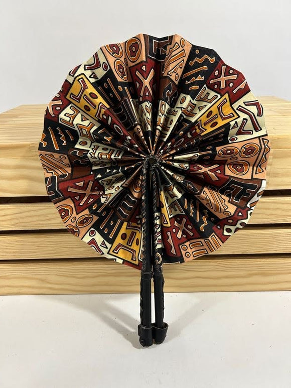 Elevate your style with our foldable handmade African fan from Ghana. Crafted with vibrant African wax print fabric and goat leather, this compact accessory is perfect for any occasion. Carry a piece of Ghana with you in your purse or bag. [Black Leather, Brown & Black Fabric] Embrace the artistry of Ghanaian craftsmanship. #Handmade #AfricanFashion #GhanaCrafts #WomenOwned #ShopWithPurpose #BusankamWolaFoundation