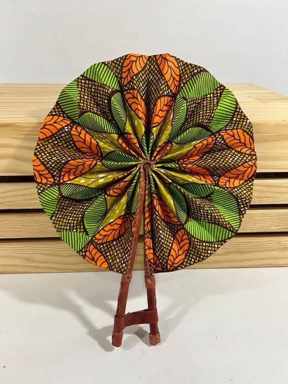 Elevate your style with our foldable handmade African fan from Ghana. Crafted with vibrant African wax print fabric and goat leather, this compact accessory is perfect for any occasion. Carry a piece of Ghana with you in your purse or bag. [Brown Leather, Brown, Green, & Orange Fabric] Embrace the artistry of Ghanaian craftsmanship. #Handmade #AfricanFashion #GhanaCrafts #WomenOwned #ShopWithPurpose #BusankamWolaFoundation